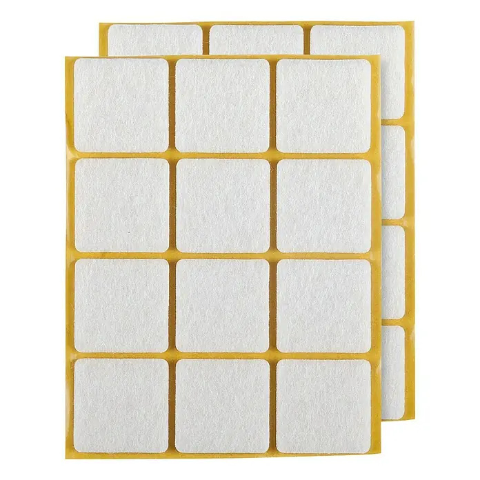 Stabilit Filzgleiter25 x 25 mm, 24 Stk., Weiß, Kleben - Dieses Bild zeigt Möbelgleiter Pads, die auf einem gelben Trägerpapier angeordnet sind. Diese Filzpads verhindern Kratzer auf Böden.