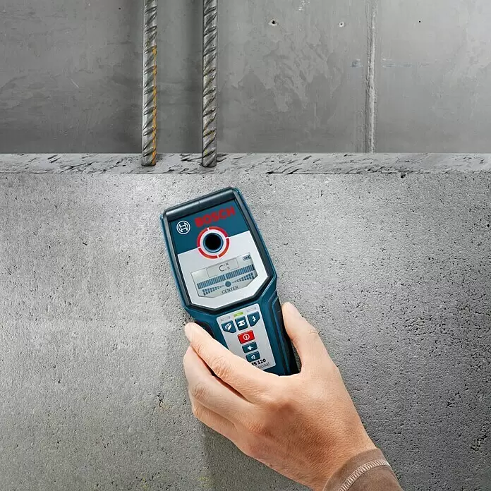 Bosch Professional Detector GMS 120 - Profundidad de detección: Máx. 120 mm de acero, Tiempo de funcionamiento: 5 h - Una mano sostiene un detector de pared Bosch azul que detecta varillas en una pared de hormigón.