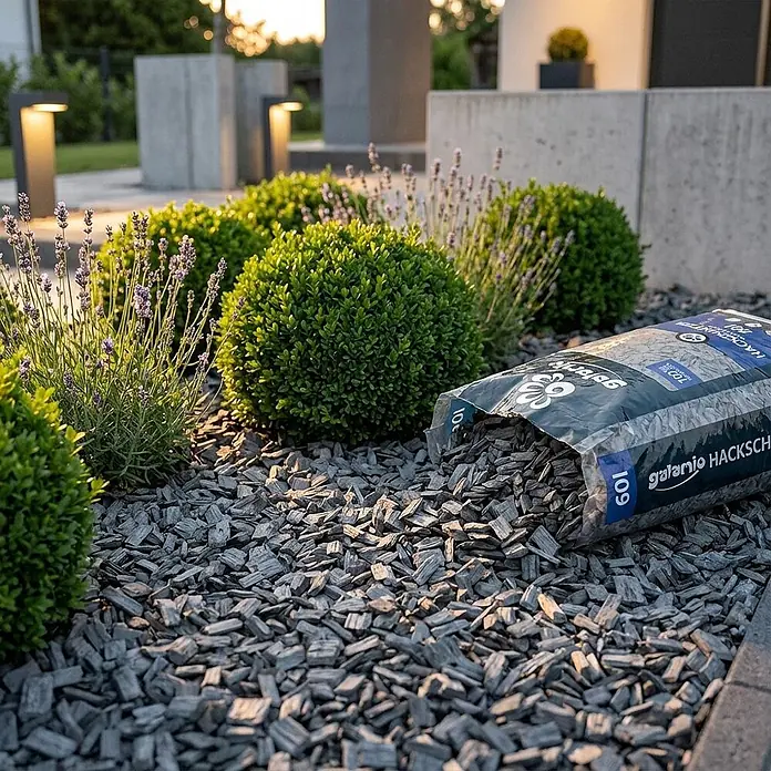 Hackschnitzel Holzdekor Grau 5-60 mm 60l -  - Sack dunkelgrauer Holzspäne ergießt sich auf ein Gartenbeet mit Buchsbaumkugeln und Lavendel.