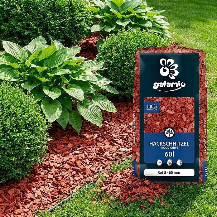 Hackschnitzel Holzdekor Rot 5-60 mm 60l -  - Sack roter Kiefern-Hackschnitzel im Garten, als Mulch unter Pflanzen ausgelegt.