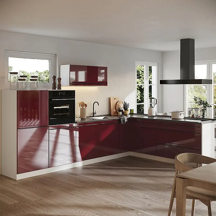 Eckküche R-Line 327 cm Rot Hochglanz Art.-Nr. 66810 -  - Moderne L-förmige Küche mit hochglänzenden bordeauxroten Schränken, dunkler Arbeitsplatte und integriertem Backofen und Spüle, in einem hellen Raum.
