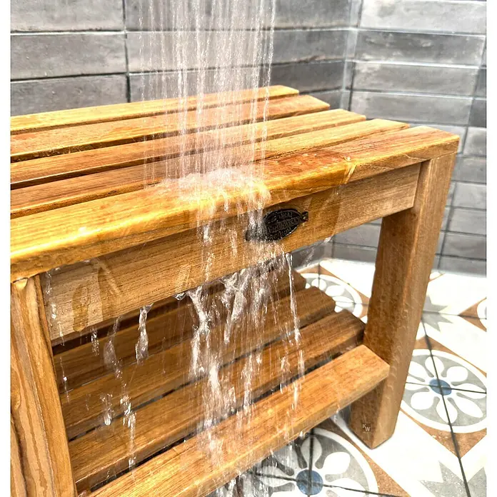 Duschhocker Holz Stella als edler Teak Duschstuhl mit Anti-Rutsch-Füßen -  - Teak-Duschhocker mit Lamellen, unter fließendem Wasser im Bad, was Wasserbeständigkeit demonstriert.