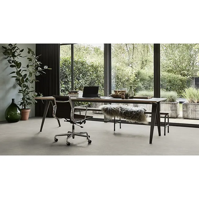 PVC-Boden Meterware Vinylboden 2m Beton grau hell -  - Modernes Home-Office mit Holzschreibtisch, dunklem Bürostuhl und einer Bank mit Fellüberwurf, vor großen Fenstern mit Gartenblick.