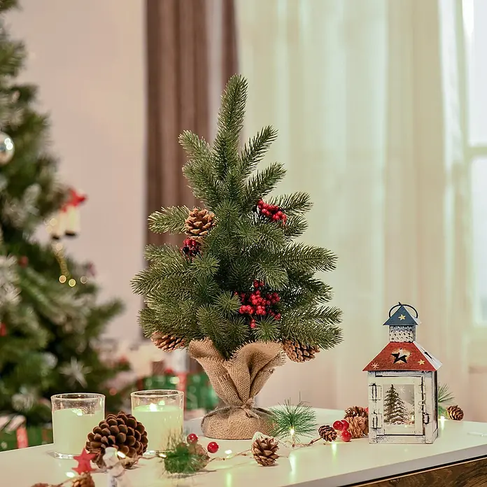 HOMCOM-Weihnachtsbaum-Ø28 x 50H cm-Grün -  - Ein kleiner künstlicher Weihnachtsbaum, mit roten Beeren und Tannenzapfen geschmückt, steht auf einem weißen Tisch zwischen festlicher Weihnachtsdekoration.