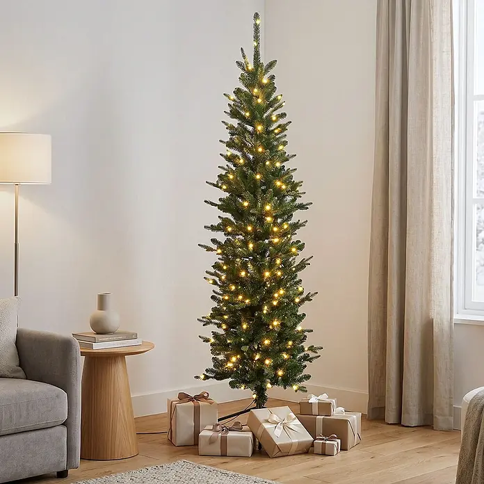 ECD Germany Künstlicher Weihnachtsbaum 180 cm mit Beleuchtung, Naturgetreu -  - Schlanker, vorbeleuchteter künstlicher Weihnachtsbaum mit warmweißen Lichtern, umgeben von Geschenken in einem modernen Wohnzimmer.