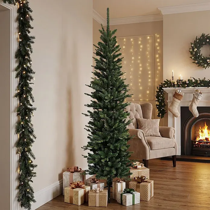 ECD Germany Künstlicher Weihnachtsbaum 180 cm, Weihnachtsdeko Innen -  - Ein schlanker, hoher grüner künstlicher Weihnachtsbaum und eine beleuchtete grüne Girlande in einem festlichen Wohnzimmer mit Geschenken und Kamin.