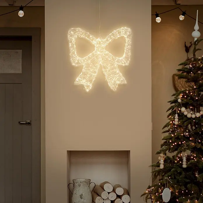 ECD Germany LED Weihnachtsschleife, Weihnachtsdeko Innen & Außen 48x46 cm -  - Eine große, beleuchtete warmweiße LED Weihnachtsschleife hängt in einem festlichen Raum als Teil der Weihnachtsdekoration.