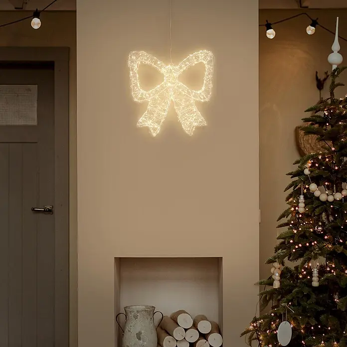 ECD Germany LED Weihnachtsschleife, Weihnachtsdeko Innen & Außen 37x33 cm -  - Eine warmweiße LED-Schleifendekoration, beleuchtet und an einer Wand als Teil einer festlichen Dekoration hängend.