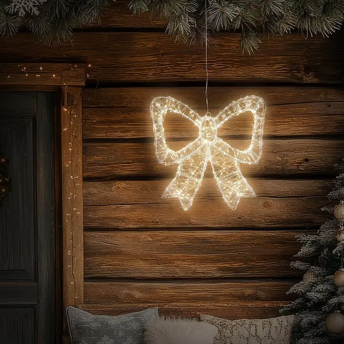 ECD Germany LED Weihnachtsschleife, Weihnachtsdeko Innen & Außen 37x33 cm -  - Eine leuchtende Schleifen-Lichterkette hängt an einer rustikalen Holzwand und verleiht einer weihnachtlichen Außendekoration eine festliche Note.