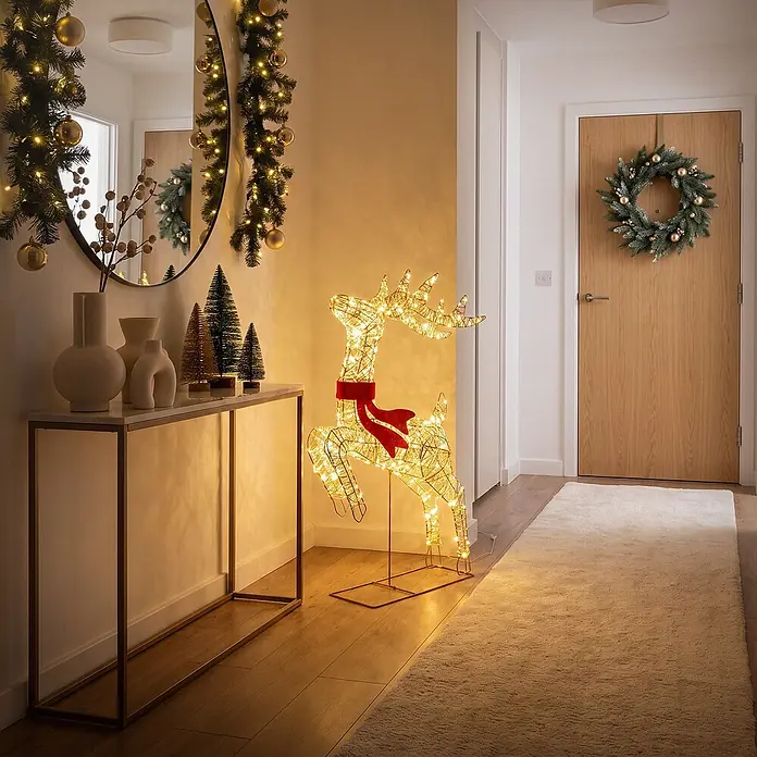 ECD Germany LED Rentier Outdoor, Weihnachtsfigur 91 cm, Weihnachtsdeko -  - Ein großes, beleuchtetes Draht-Rentier mit rotem Schal steht in einem dekorierten Flur und spendet warmes Licht.