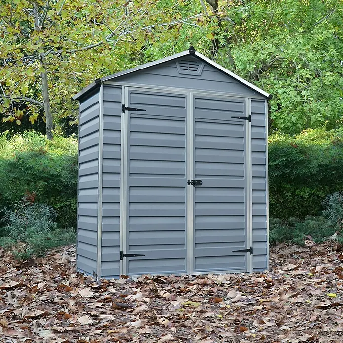 Palram – Canopia Caseta de jardín Skylight - Medidas ext. (An x Pr): 185 x 90 cm, Plástico, Gris oscuro - Cobertizo gris con puertas dobles en un jardín con hojas caídas alrededor. Ideal para guardar herramientas de jardín.
