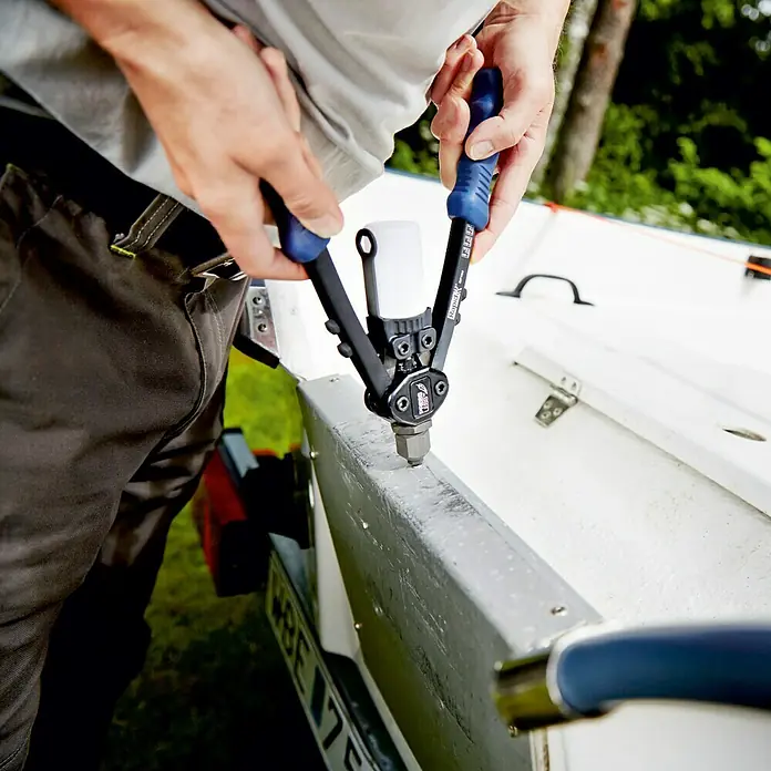 Rapid Blindniete - Nietlänge: 14 mm, Nietdurchmesser: 4,8 mm, 50 Stk. - Eine Person benutzt eine Rapid RP110 Nietzange, um Nieten an einem Boot zu befestigen. Das Werkzeug hat blaue Griffe für Komfort.