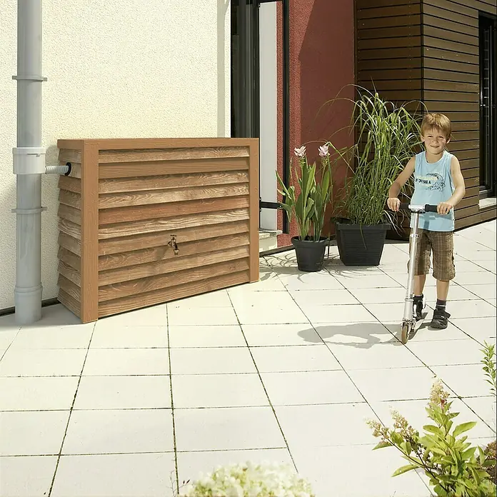 Garantia Exklusive Line Regenspeicher Woody - 350 l, Lightwood - Holzregentonne mit Kind auf Roller vor dem Haus. Die Regentonne ist aus hellem Holz und hat eine Pumpe.