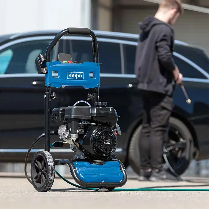 Scheppach Hochdruckreiniger HCP5000 - 4,3 kW, Max. Druck: 241 bar, Fördermenge: 590 l/h - Blauer und schwarzer Scheppach Hochdruckreiniger auf Rädern, aktiv zum Reinigen eines dunklen Autos verwendet.