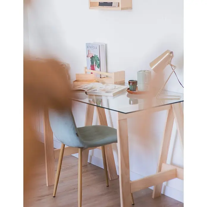 Astigarraga Encimera de cristal con caballetes - Vidrio templado, Pino, 120 x 60 cm - Una oficina en casa con un escritorio de madera clara y cristal, una silla tapizada azul claro y una lámpara de mesa dorada.