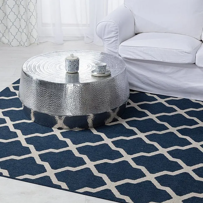Dekoria Teppich Cottage blue/beige 160x230cm -  - Runder gehämmerter silberner Couchtisch und blauer geometrischer Teppich in einem Wohnzimmer mit weißem Sofa.