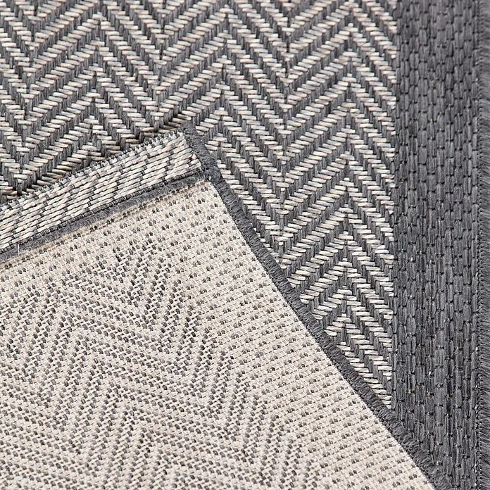 Dekoria Teppich Breeze cliff grey 200x290cm -  - Grauer und beiger gewebter Teppich mit Chevron-Muster, eine Ecke zeigt die texturierte Unterseite.