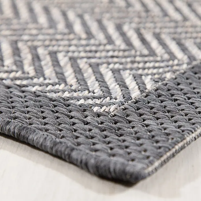 Dekoria Teppich Breeze cliff grey 200x290cm -  - Nahaufnahme eines gewebten Teppichs mit dunkelgrauem und hellgrauem Chevron-Muster.