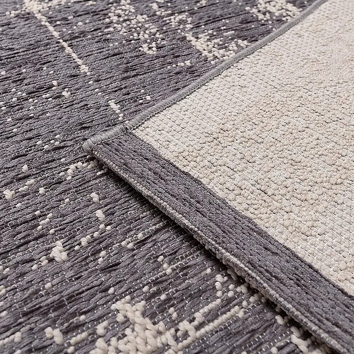 Dekoria Teppich Velvet beige/dark grey 200x290cm -  - Nahaufnahme eines grau-cremefarbenen Teppichs, zeigt seine strukturierte Oberfläche und hellere Rückseite.