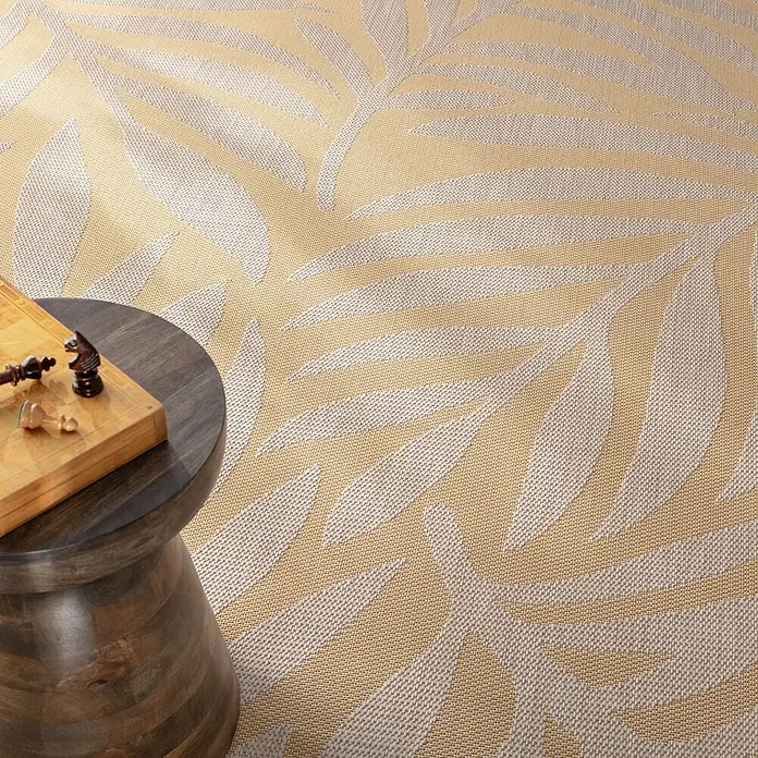 Dekoria Teppich Avenna golden beige 160x230 cm -  - Ein beiger und gelber Teppich mit Blattmuster, teilweise verdeckt von einem kleinen Holztisch mit Schachbrett.