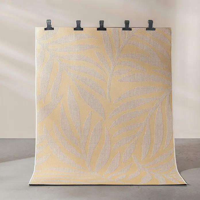Dekoria Teppich Avenna golden beige 160x230 cm -  - Gelb-beiger gewebter Teppich mit tropischem Blattmuster, vertikal ausgestellt und oben mit Klammern gehalten.
