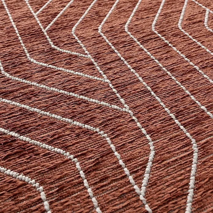 Dekoria Teppich Velvet beige/rust 120x170cm -  - Nahaufnahme eines terrakottafarbenen Textils mit ausgeprägter Webstruktur und geometrischem Muster aus weißen Zickzacklinien.