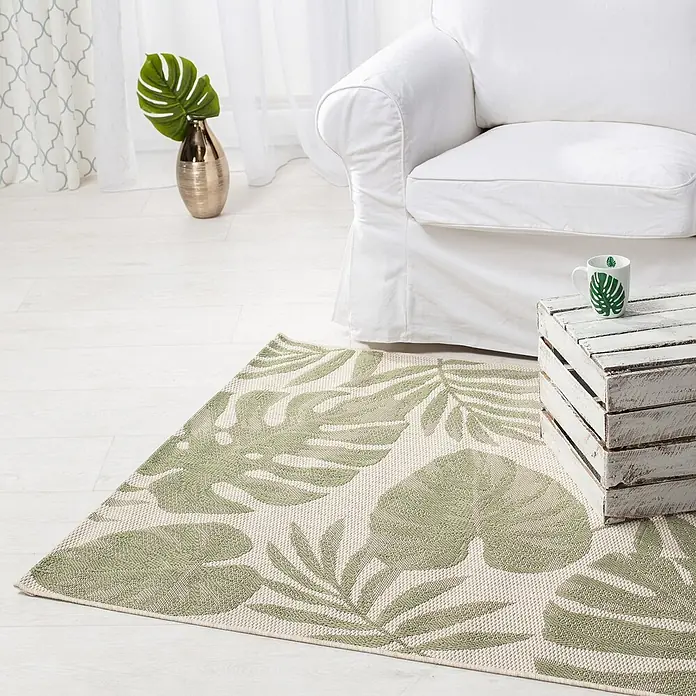 Dekoria Teppich Cottage beige/jungle green 120x170cm -  - Grün-beiger Teppich mit tropischem Blattmuster auf hellem Boden neben einem weißen Sofa.