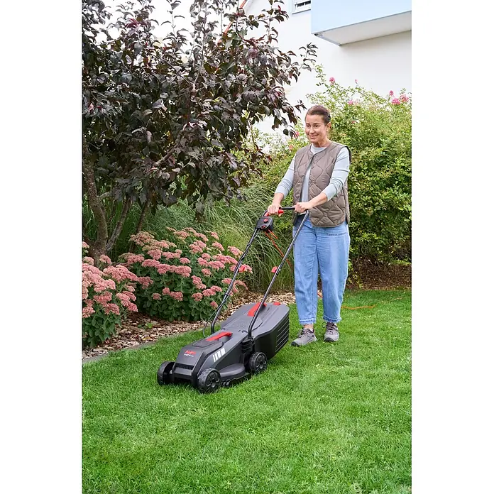 AL-KO Elektro-Rasenmäher 3.87 E - 1.400 W, Schnittbreite: 38 mm, Max. Flächenempfehlung: 500 m² - Eine Frau mäht einen grünen Rasen mit einem schwarz-roten Elektrorasenmäher, der in einem Garten benutzt wird.