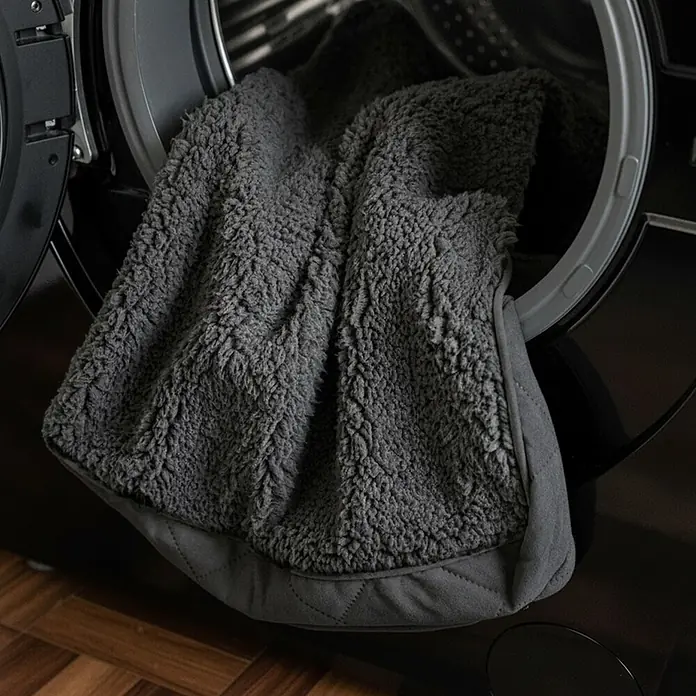 belviona Hundebett 91x69 cm, orthopädisch, Bezug waschbar, schwarz -  - Dunkelgraue flauschige Decke mit gestepptem Rand, teilweise in einer Waschmaschine.