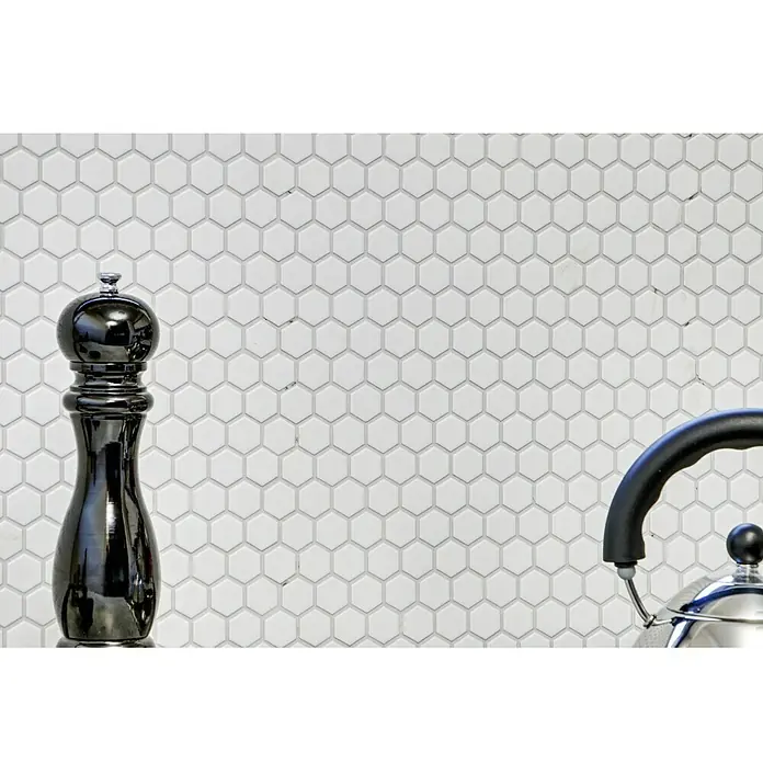 Mosaikfliese Hexagon Uni HX 055 - 26 x 30 cm, Weiß, Matt - Nahaufnahme einer schwarzen Pfeffermühle und eines Teekessels vor einem Hintergrund aus sechseckigen Fliesen.
