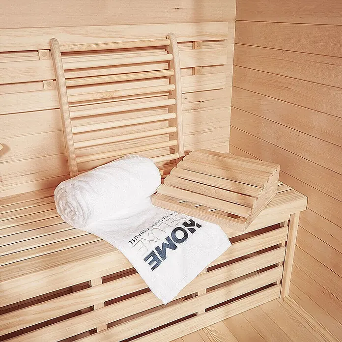 Home Deluxe Sauna-Zubehör RAJA -  - Sauna-Innenraum aus Holz mit Bänken, Rückenlehne, Fußhocker und weißem Handtuch.