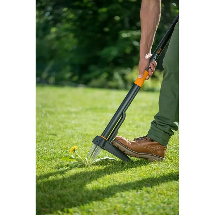 Fiskars Xact Unkrautstecher - Mit Greifarmen, Länge: 100 cm - Nahaufnahme eines Fiskars Unkrautstechers im Einsatz. Das Gerät entfernt Unkraut mühelos aus dem Rasen, ohne Bücken.
