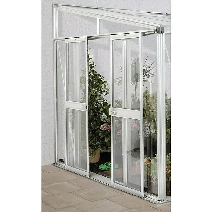 Vitavia Gewächshaus-Tür - Passend für: Vitavia Gewächshaus Helena, Aluminium - Ein Gewächshaus mit Schiebetüren, bepflanzt mit verschiedenen Pflanzen und grünem Schuhwerk im Inneren. Das Gewächshaus hat einen silbernen Rahmen.