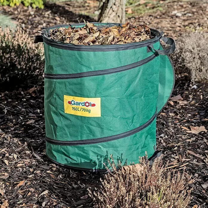Gardol Premium Saco para desechos de jardín Pop-Up - 150 l, Ø x Al: 56 x 61 cm - Una bolsa de jardín plegable verde, llena de hojas secas, se encuentra en un jardín.