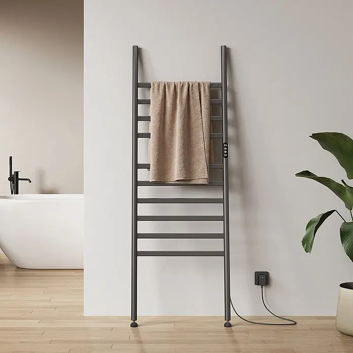 Elektro-Badheizkörper PFLR2 1600 × 550 × 32 mm Gunmetal -  - Dunkelgrauer freistehender elektrischer Handtuchwärmer mit beigem Handtuch, in einem modernen Badezimmer an eine Steckdose angeschlossen.