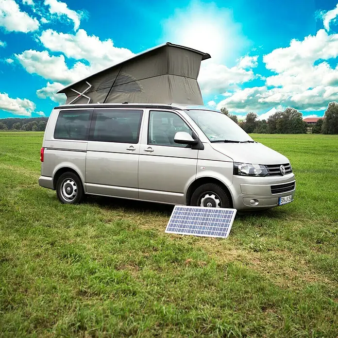 Sunset Solarmodul-Set Caravan - Nennleistung: 60 W, Für den Caravan- und Campingbereich - Ein silberner VW-Campingbus mit ausklappbarem Dach und einer tragbaren Solarpanel auf einer grünen Wiese unter blauem Himmel.