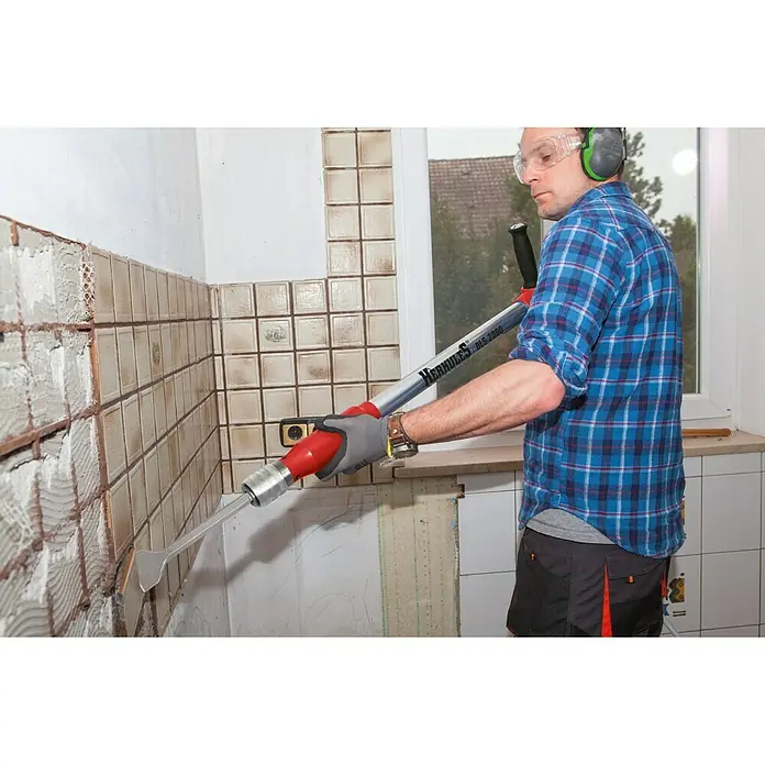 Herkules Multiherramienta neumática - 6,3 bar, Consumo de aire: 160 - 280 l/min - Un hombre quita azulejos con un quitazulejos Herkules DLS 2000, que simplifica la extracción gracias a su apalancamiento.