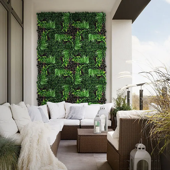 Künstliche Pflanzenwand Kunstpflanzen Wand Innen Aussen Jungle Fern -  - Üppige künstliche Grünwand auf einem Balkon mit Korbmöbeln und weißen Kissen für einen gemütlichen Außenbereich.