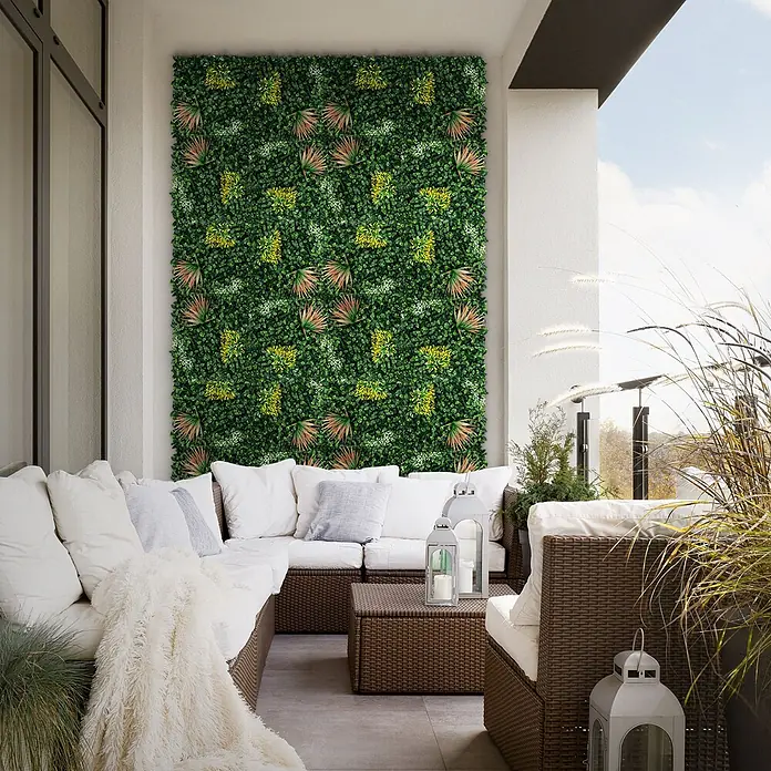Künstliche Pflanzenwand Kunstpflanzen Wand Innen Aussen Copper Leaf -  - Künstliche grüne Wandpaneele bilden eine üppige Kulisse auf einem Balkon, ergänzend zu Outdoor-Sitzmöbeln.