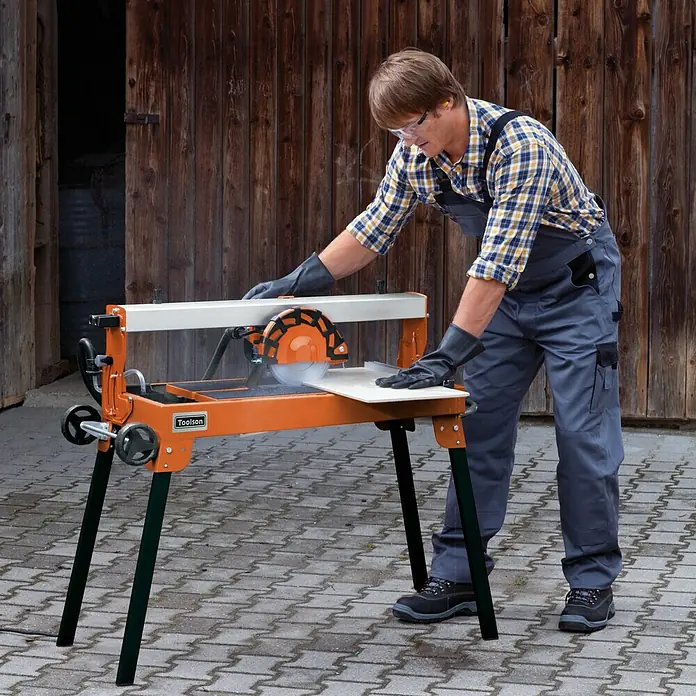 Toolson Elektro-Fliesenschneider PRO-RF 620 - 900 W, Max. Schnittlänge: 620 mm, Schnitttiefe bei 90 °: 30 mm - Ein Arbeiter, der mit der Fliesenschneidmaschine Toolson Fliesen schneidet, die sich ideal zum präzisen Schneiden von Fliesen eignet.