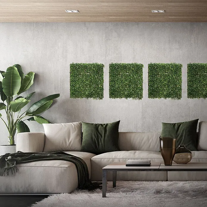 Künstliche Pflanzenwand Kunstpflanzen Wand Innen Aussen Classic Buxus -  - Vier quadratische Kunstpflanzen-Paneele schmücken eine Betonwand über einem hellen Sofa und verleihen dem Wohnraum einen natürlichen Akzent.