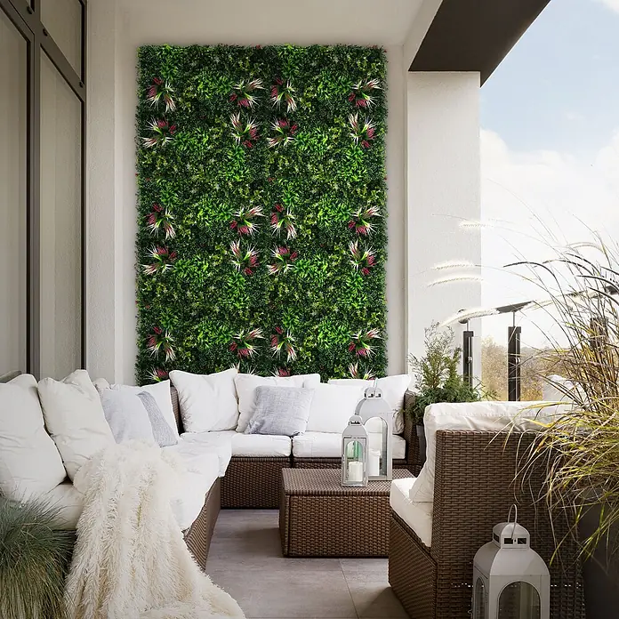 Künstliche Pflanzenwand Kunstpflanzen Wand Innen Aussen Tropical Pink -  - Vertikale grüne Wand mit künstlichem Laub und rosa Akzenten, die einen modernen Balkon über Sitzgelegenheiten schmückt.