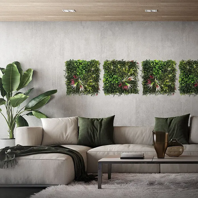 Künstliche Pflanzenwand Kunstpflanzen Wand Innen Aussen Tropical Pink -  - Vier quadratische künstliche Grünwandpaneele mit roten und weißen Akzentpflanzen, die eine Wohnzimmerwand über einem beigen Sofa schmücken.