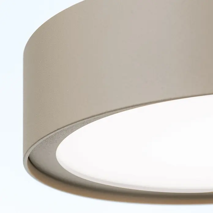 Orion Leuchten Pendelleuchte Teide Grau -  - Nahaufnahme einer runden Leuchte mit beigem, texturiertem Metallrand und einem leuchtend weißen Diffusor.