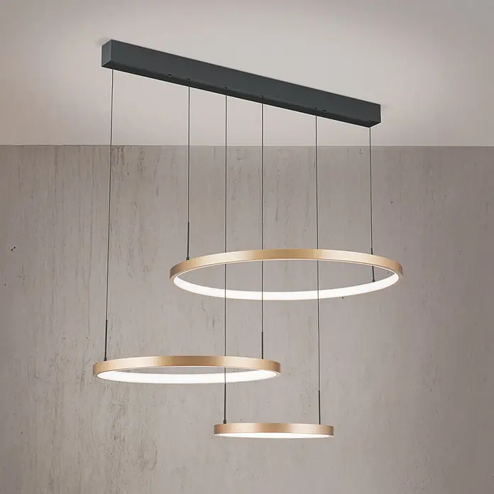 Orion Leuchten Pendelleuchte Ringe -  - Moderne Pendelleuchte mit drei goldenen Ringen unterschiedlicher Größe, integrierten LED-Leuchten, von dunkler rechteckiger Deckenhalterung abgehängt.