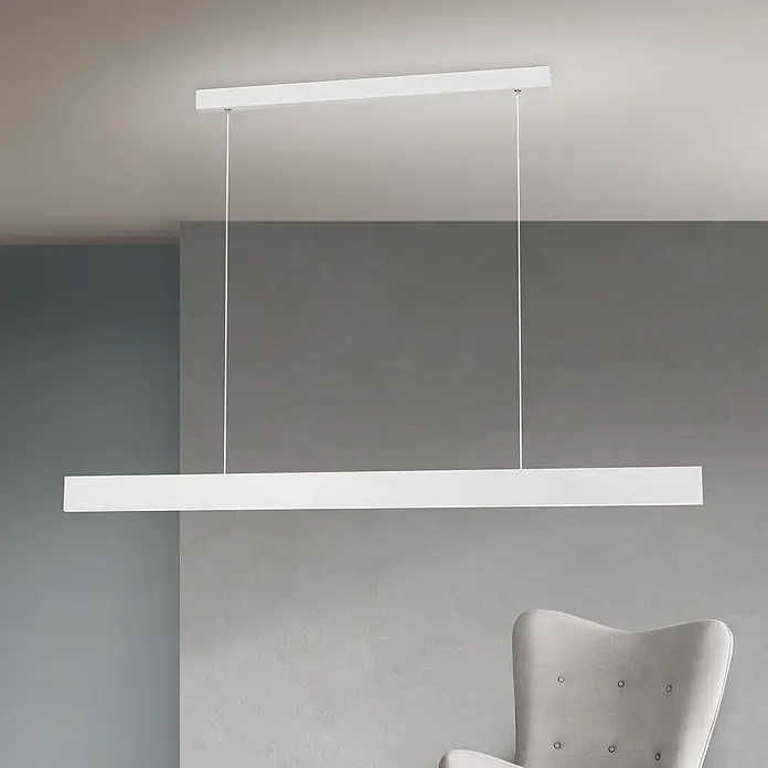 Orion Leuchten Pendlleuchte Gideon Weiß -  - Eine moderne, lineare weiße LED-Pendelleuchte hängt von der Decke in einem Raum mit grauer Wand und Sessel.