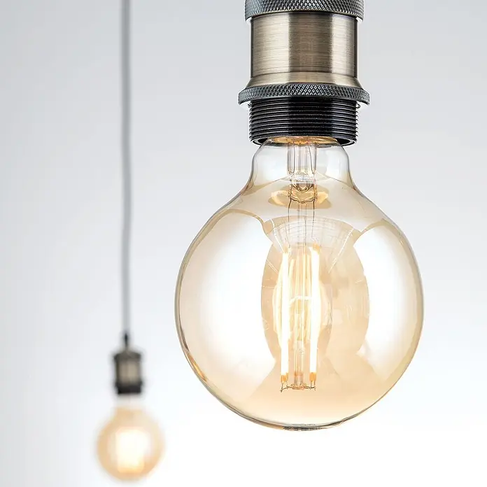 Orion Leuchten Hängelleuchte Vintage -  - Warme bernsteinfarbene Vintage-LED-Filamentbirne mit messingfarbener Fassung, als Pendelleuchte hängend.