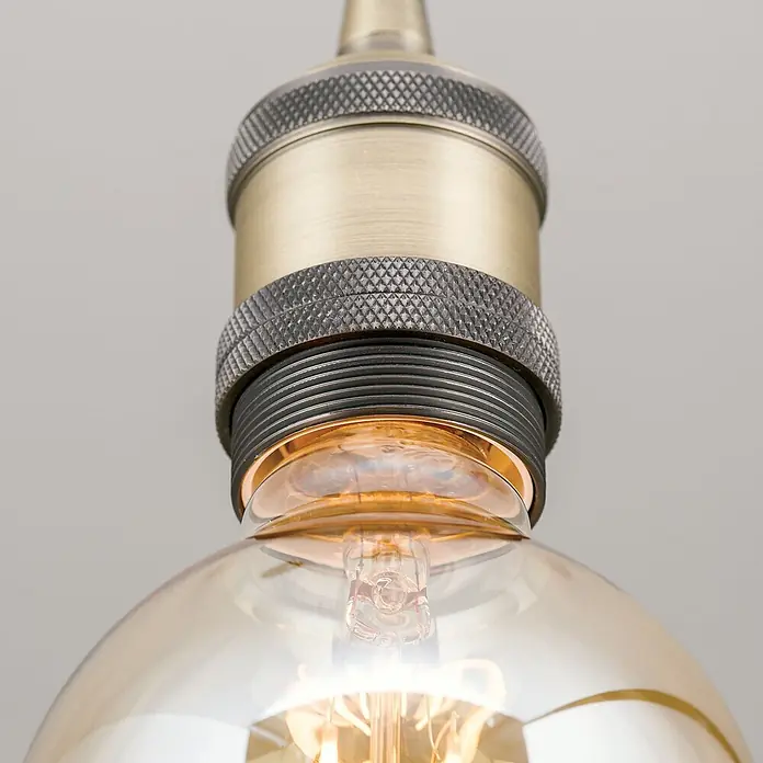 Orion Leuchten Hängelleuchte Jailhouse -  - Detailaufnahme einer messingfarbenen Lampenfassung mit Rändelungen und bernsteinfarbener Vintage-LED-Glühbirne.
