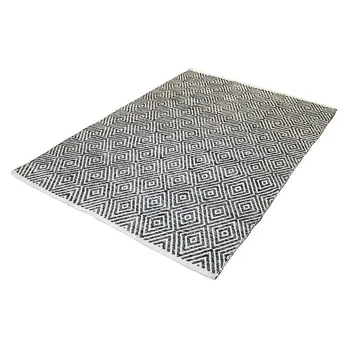 Kayoom Flachgewebeteppich Cocktail 300 - Grau, 150 x 80 cm, 100% Baumwolle - Bild eines rechteckigen Teppichs mit einem sich wiederholenden Rautenmuster in Schwarz und Weiß, der auf einem weißen Hintergrund liegt.