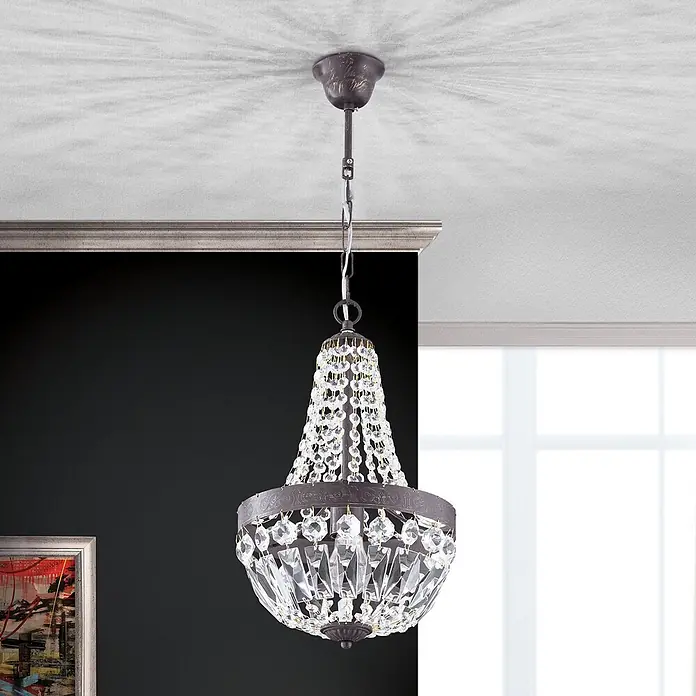 Orion Leuchten Kronleuchter Arila Ø 25 cm -  - Eleganter Kristall-Kronleuchter mit dunklem Bronzerahmen hängt von der Decke und beleuchtet einen Raum.